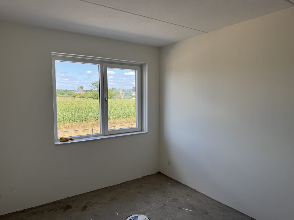 Kamer met gladde, lichte wanden en een raam met uitzicht op het land